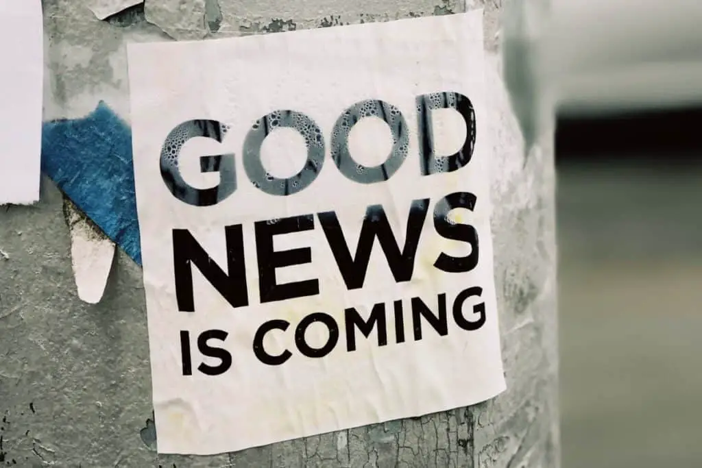 A laminated sign on a tree that reads "Good News is Coming"