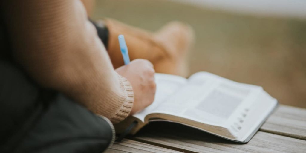 A person studying the Bible with a pen in hand